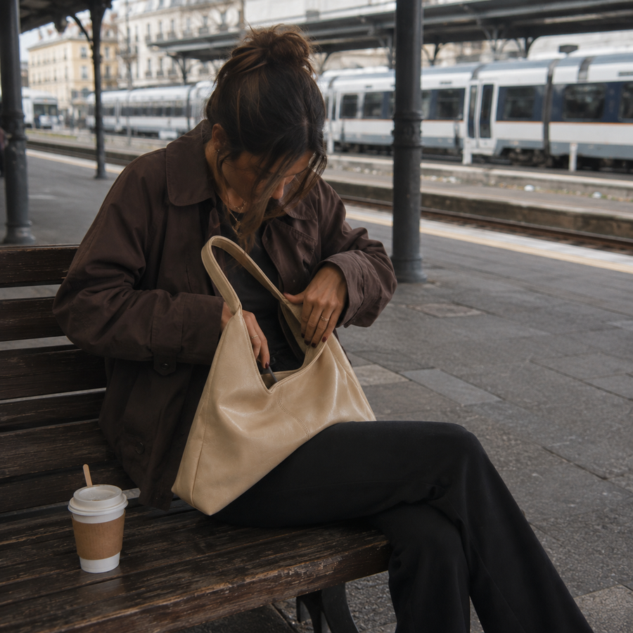 Bolso Firenze beige sentada en un banco de la estación