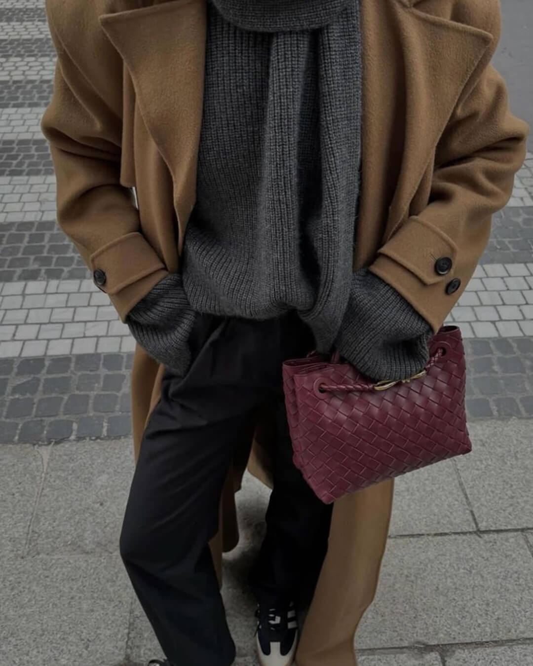 Bolso Capri tejido en burdeos llevado en la mano con abrigo camel